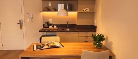 A modern kitchen with a dining area, including a wooden table, chairs, and a potted plant.