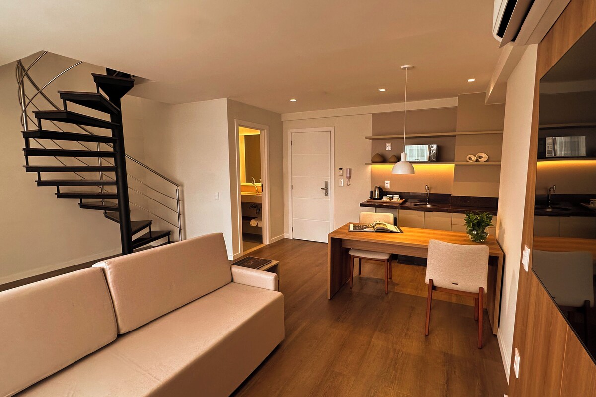 Una sala moderna con una escalera, una zona de comedor y una cocina.