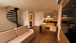Una sala moderna con una escalera, una zona de comedor y una cocina.