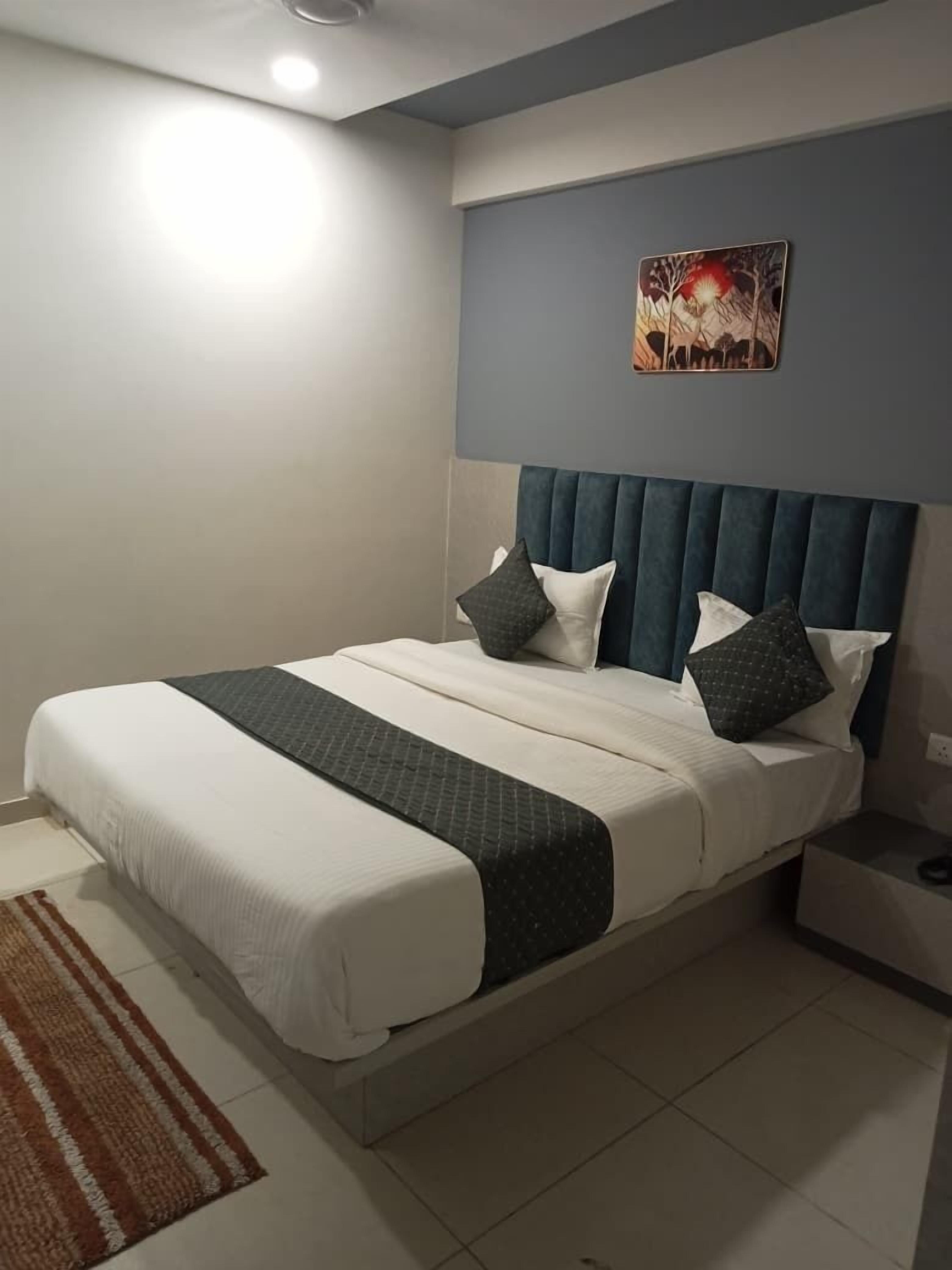 Un dormitorio ordenado con una cama, una mesita de noche y una obra de arte colgada en la pared.