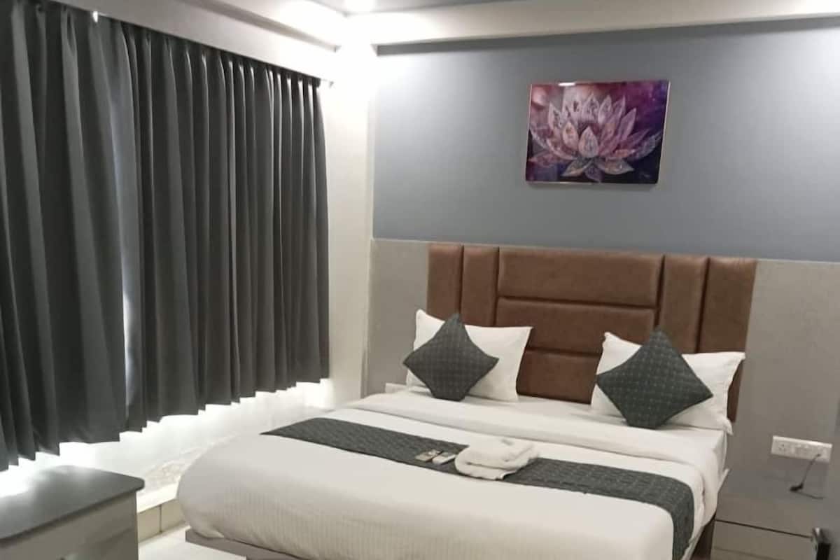 A modern bedroom with a large bed, a nightstand, a chair, and a wall-mounted artwork.