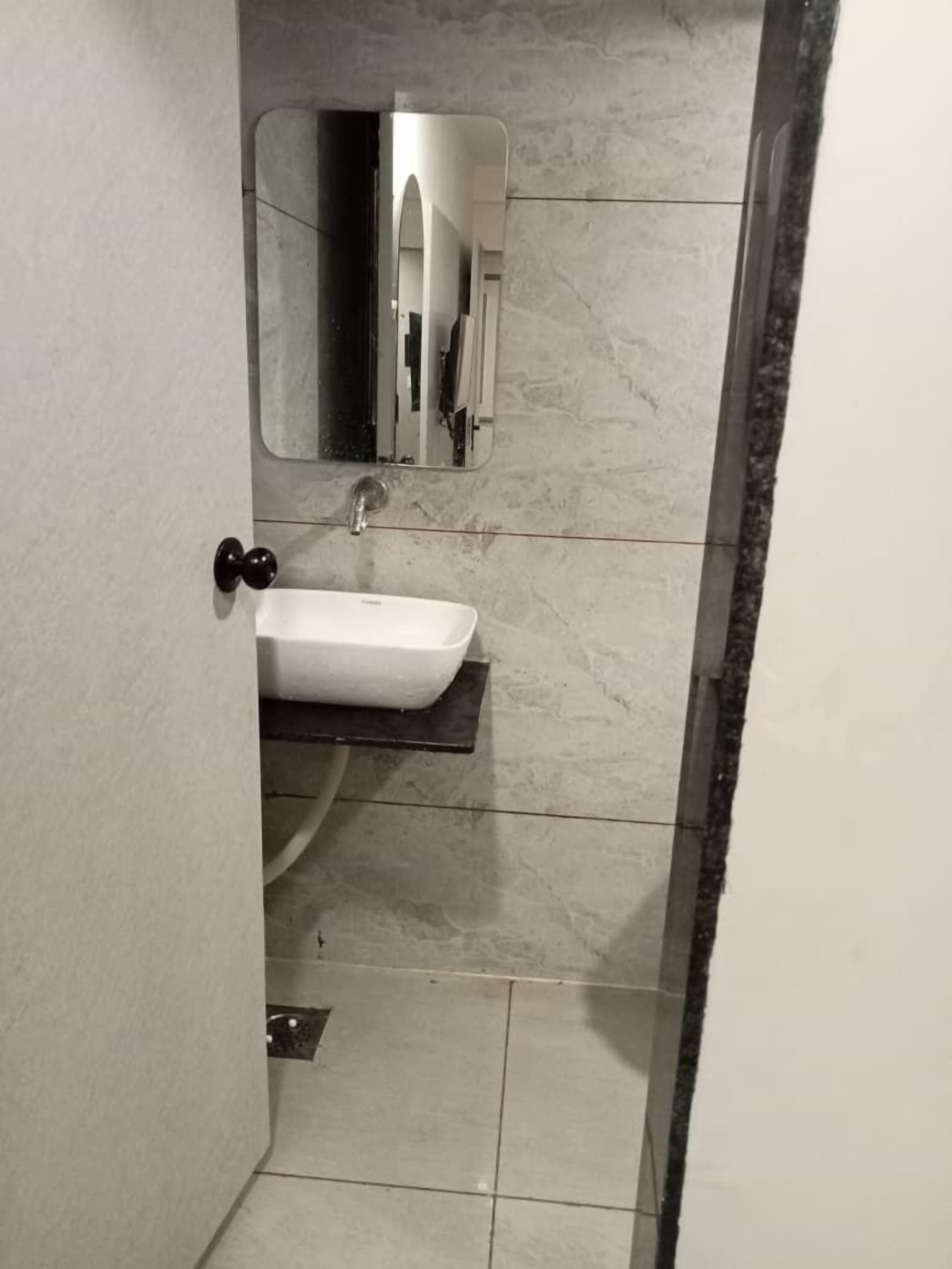 Een badkamer met een wit wastafelmeubel, een spiegel en een betegelde vloer.