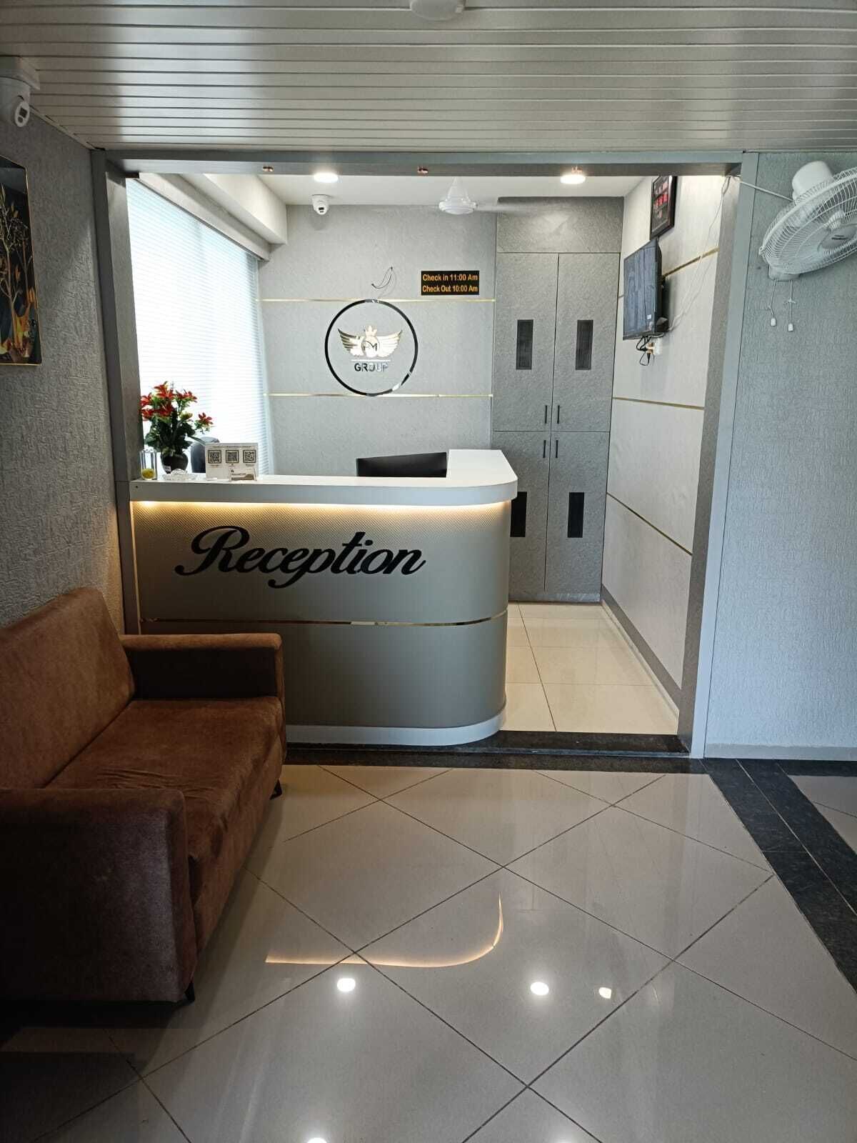 A reception area with a reception desk labeled "Reception," a brown sofa, and a sign indicating check-in and check-out times.