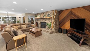 A modern living room with a stone fireplace, a large flat-screen TV, a sectional sofa, and a wooden coffee table. - Cr2232k-2 (Keystone)