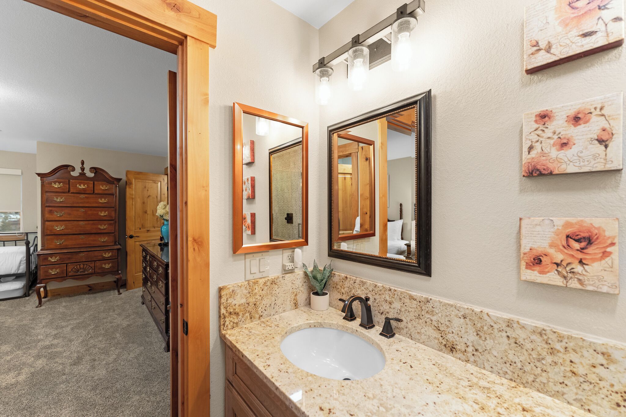 A bathroom with a granite sink, wooden vanity, and a large mirror.