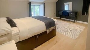 Une chambre à coucher moderne avec un lit, un bureau et un grand miroir.
