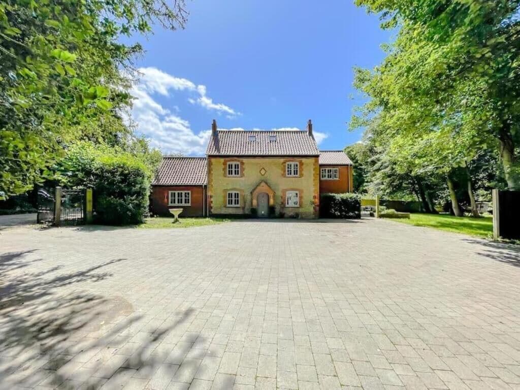 A large, two-story house with a tiled roof, a central entrance, and a paved driveway.