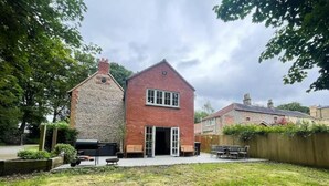 Une maison à deux étages avec une façade en pierre et une extension en briques.