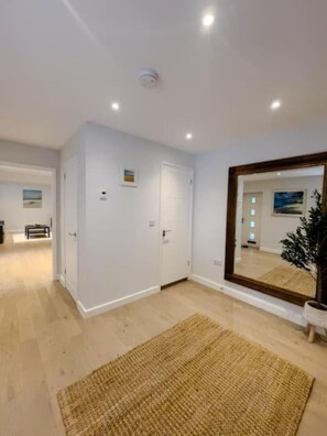 A spacious room with a large mirror, a wooden floor, and a door leading to another room. - The Gatehouse (Holt)