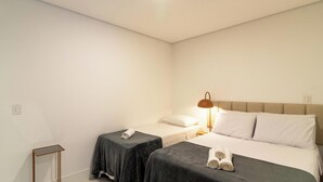 Une chambre d’hôtel avec un lit, deux tables de chevet, une lampe et des serviettes.