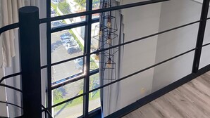 Une pièce dotée d’une grande fenêtre, de rideaux, d’un appareil de climatisation et d’un luminaire au design géométrique.