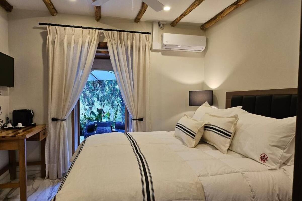 Een slaapkamer met een bed, een bureau, een airconditioner en uitzicht op bomen.