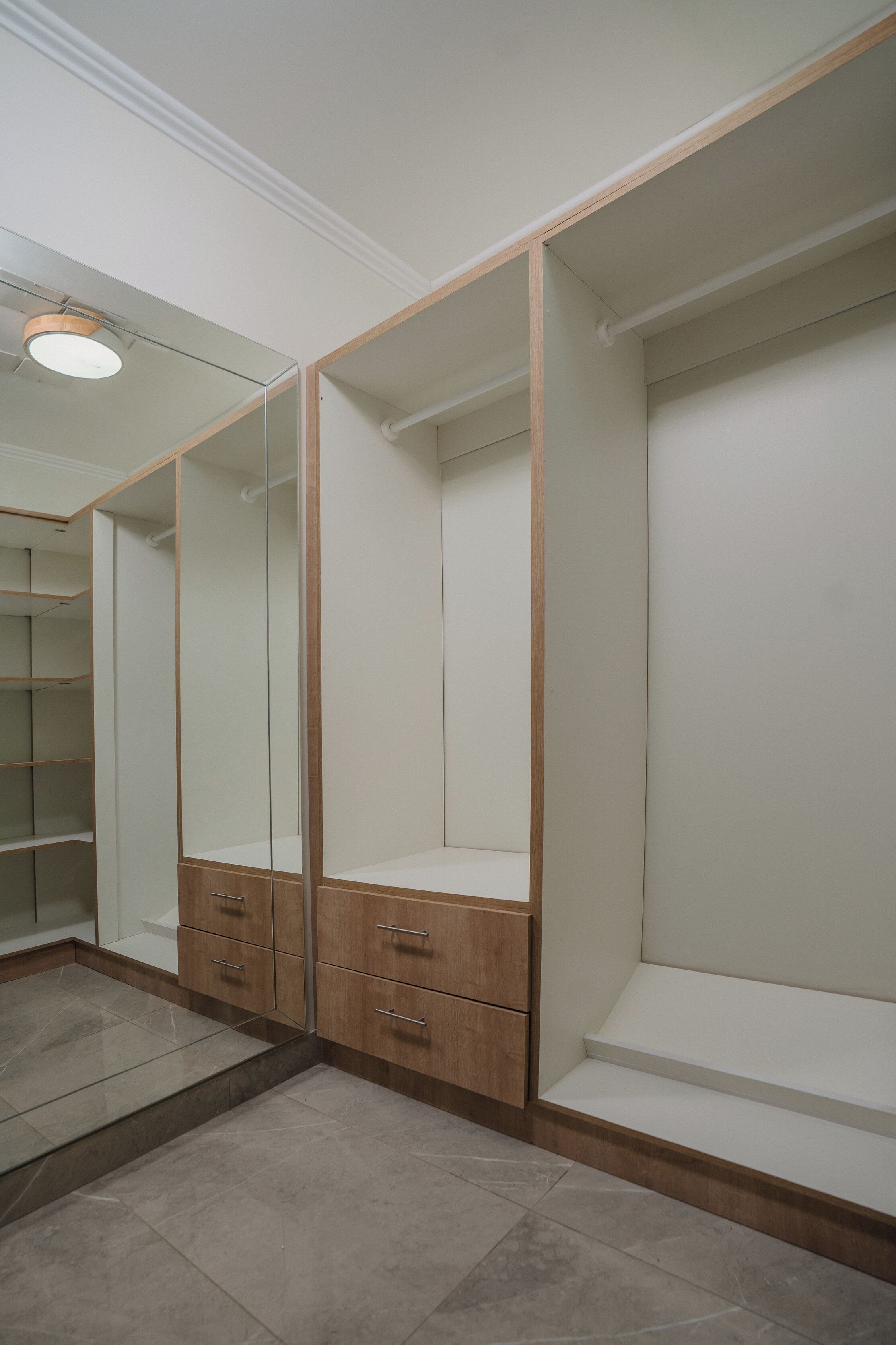 Un vestidor con puertas de madera, una sección con espejo y suelo de baldosas.