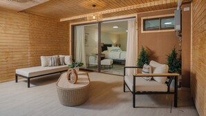 Ein modernes Interieur mit Holzboden, einer Couch, einem Sessel und einem Korbsessel.