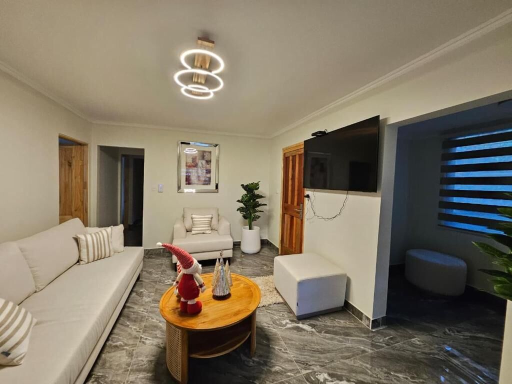 A modern living room with a sofa, a coffee table, a TV, and a plant.