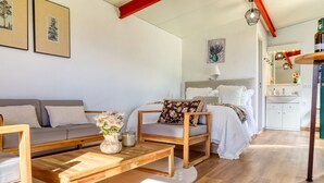 Un soggiorno moderno con un divano, un tavolino in legno e un letto con testiera.