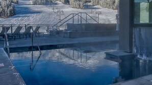 Ein Poolbereich mit Blick auf einen verschneiten Berg und eine Skipiste.