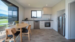 Una cucina moderna con zona pranzo, ampie finestre e vista sull'esterno.