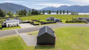 Un quartiere residenziale con case, una strada e un lago con montagne sullo sfondo.