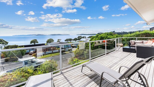 Una terraza con mobiliario exterior que ofrece vistas panorámicas del mar y una zona residencial.