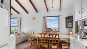 Un comedor con una mesa y sillas de madera, un sofá y vista al mar.