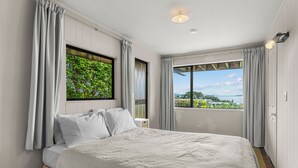 Un dormitorio con una cama grande, una ventana con vistas a la vegetación y una lámpara en el techo.