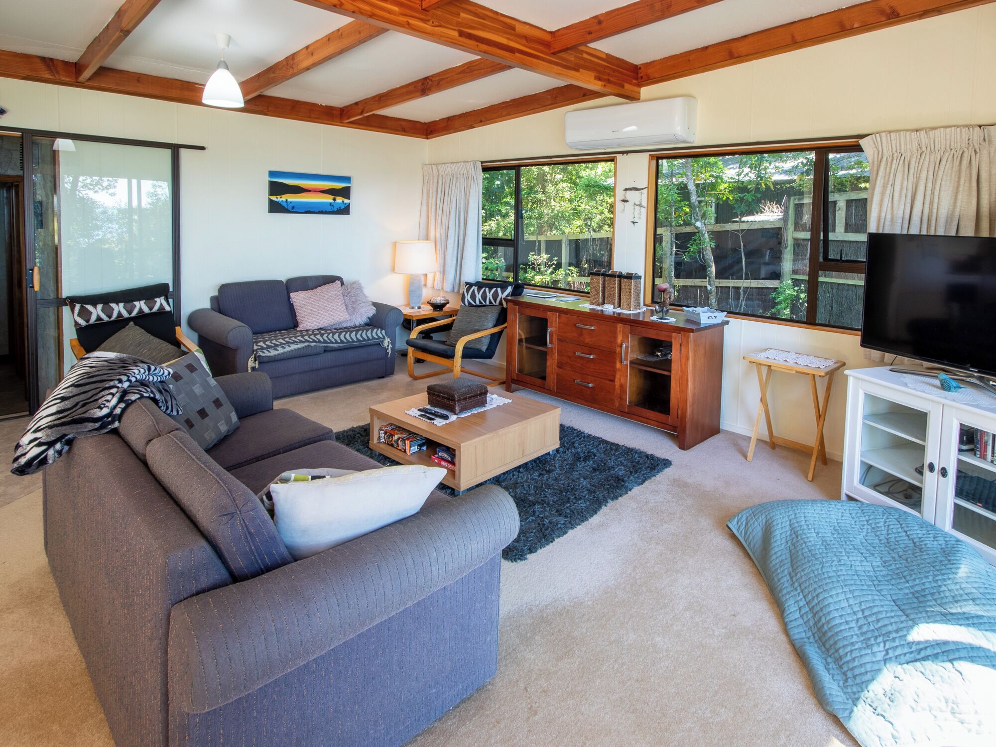 A cozy living room with a sofa, a coffee table, a TV, and a wooden cabinet.