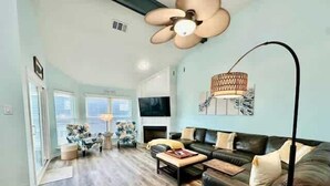 A spacious living room with a black leather sofa, wooden coffee table, and a large floor lamp. - Saltwater Solace, For 8 (Galveston)