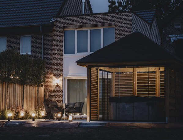 A brick house with a covered patio area, outdoor seating, and a wooden structure with shutters. - Peaceful Holiday Home Near Hannut (Hannut)