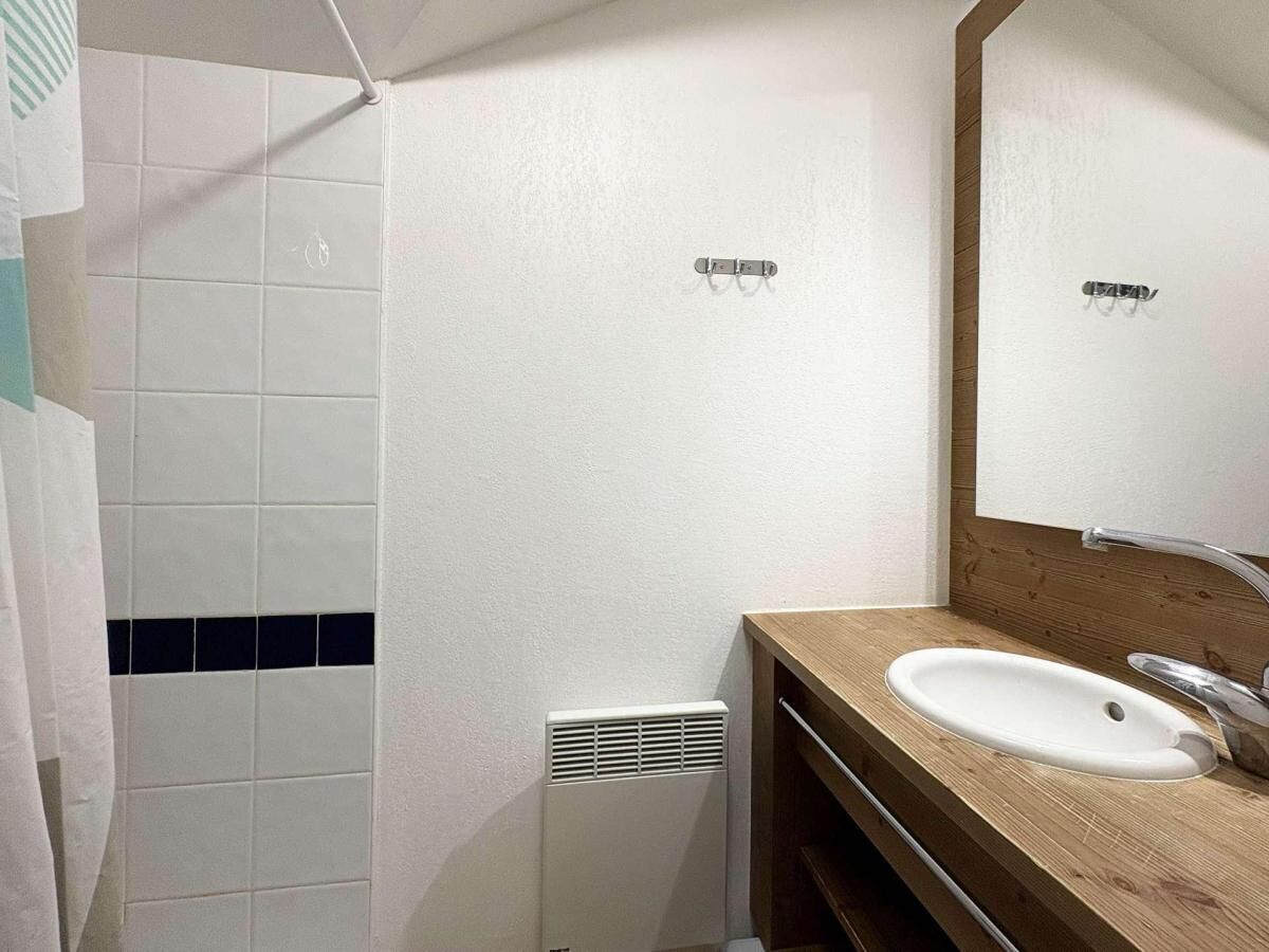A bathroom with a white sink, wooden vanity, and a mirror.