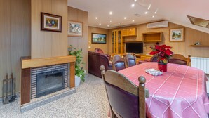 A dining area with a fireplace, wooden panel walls, a television, and a table with a red tablecloth. - Penthouse 'Pensado Para Ti' in Pozuelo de Alarcón - Central Madrid Area (Pozuelo de Alarcón)
