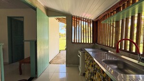 Una cocina con un lavamanos, una estufa y una ventana con persianas verticales.