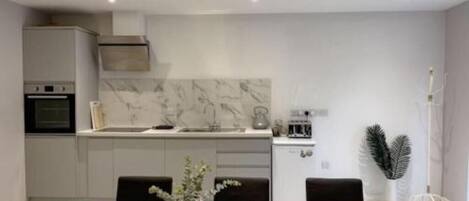 A modern kitchen with a marble backsplash, a dining table with chairs, and a small plant on the table.