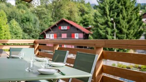 A table set outdoors with chairs, a wooden bench, and a house with red trim in the background. - Spacious Apartment 4br/10p - Megeve Center (Megeve)
