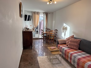 A cozy living area with a sofa, a small table, a fan, a TV, and a dining table with chairs. - THE CHARMING ONE-BEDROOM APARTMENT AT 15 RUE DE LA FRATERNITE (Drancy)