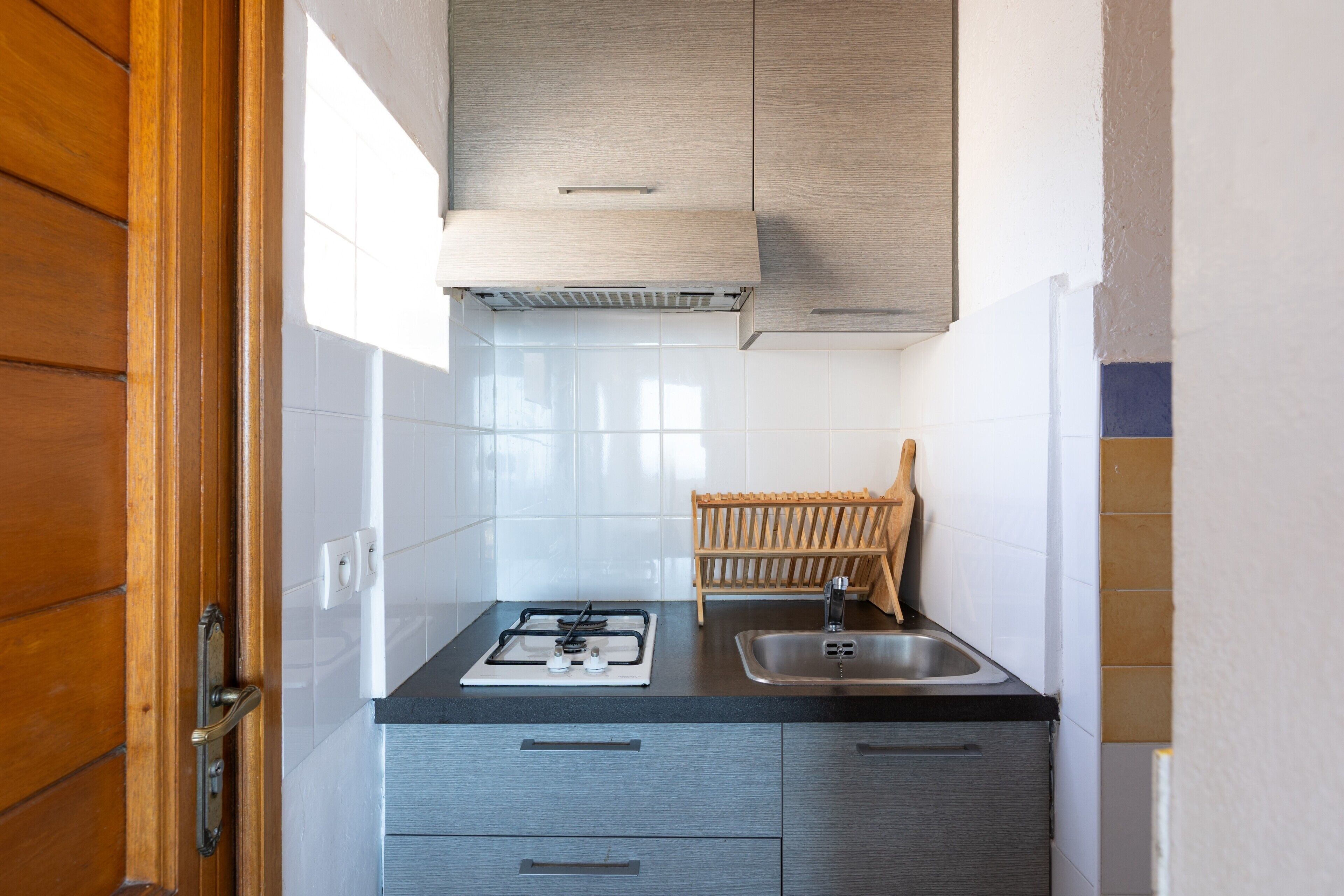 A kitchen with a gas stove, sink, and wooden drying rack.
