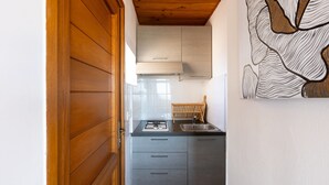 A kitchen with a wooden door, a sink, and a stove. - Studio 26m² “Marina de Sant Ambroggio” with Sea View, Terrace, Wi-Fi & Air Conditioning (Lumio)
