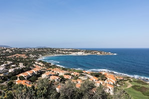 A coastal residential area with houses, a clear blue sky, and the ocean.