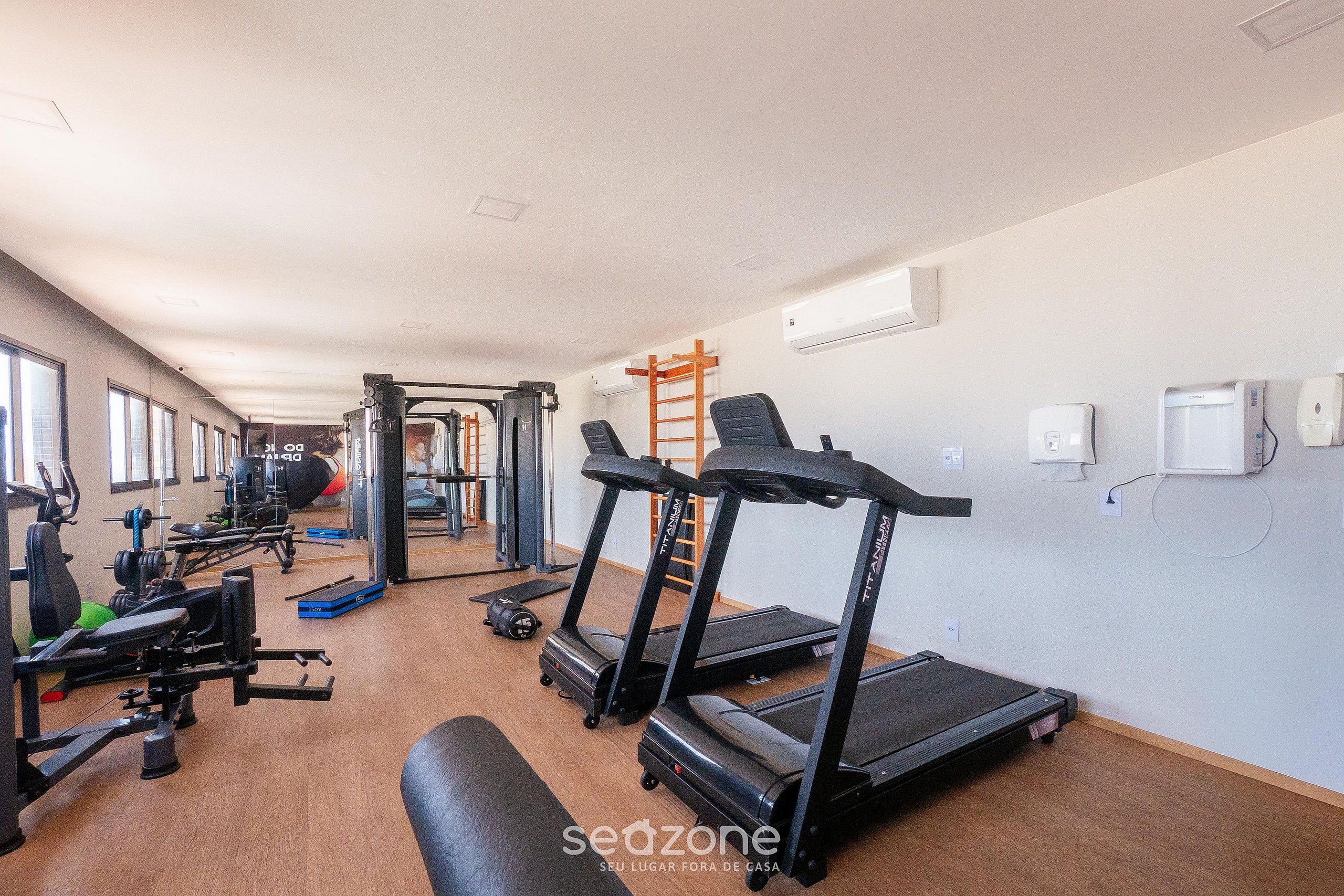Una palestra con tapis roulant, macchinari per pesi e una panca.