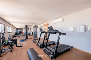 Ein Fitnessstudio mit Laufbändern, Kraftgeräten und einer Bank.