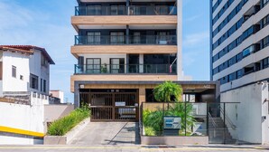 Un immeuble à plusieurs étages, doté d’une architecture moderne, comprenant une entrée sécurisée par un portail, un escalier et une enseigne indiquant le numéro 402.
