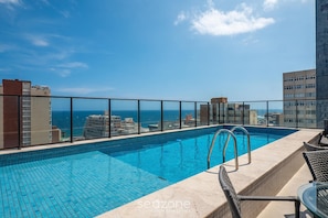 Ein Pool auf dem Dach mit freiem Blick auf das Meer und die umliegenden Gebäude.