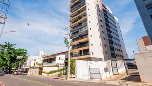 Un immeuble à plusieurs étages doté de balcons, d’une entrée sécurisée et surplombant un ciel dégagé.