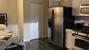 A compact kitchen with a refrigerator, microwave, oven, and a ceiling fan. - Cozy Hideaway, a studio with fireplace, full kitchen, washer, dryer poor in yard (Las Vegas,)