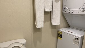 A bathroom with a toilet, a washing machine, and a towel rack. - Cozy Hideaway, a studio with fireplace, full kitchen, washer, dryer poor in yard (Las Vegas,)