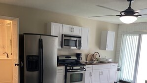 A bedroom with a bed, a kitchen with a refrigerator, stove, microwave, and cabinets. - Cozy Hideaway, a studio with fireplace, full kitchen, washer, dryer poor in yard (Las Vegas,)