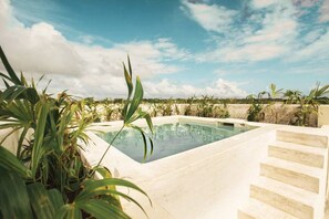 A rectangular swimming pool with a clear blue sky and clouds in the background. - Depa 2 rec y alberca privada en veleta Tulum (Tulum)