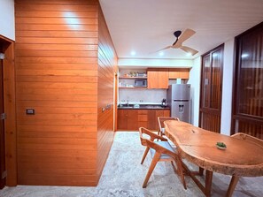 A modern kitchen with wooden cabinetry, a dining table with chairs, and a ceiling fan. - Depa 2 rec y alberca privada en veleta Tulum (Tulum)