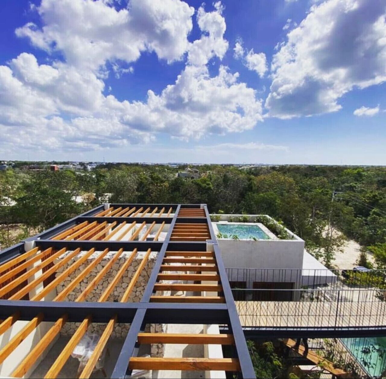 Una terrazza sul tetto con piscina, un pergolato in legno e vista sul paesaggio circostante.