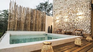 Una piscina con recinto in bambù, muro in pietra e terrazza in legno con lanterne.